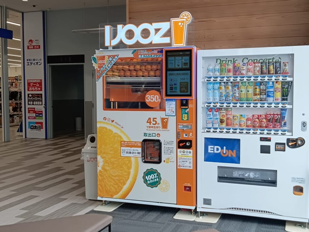 メディアでも話題の生搾りオレンジジュース自販機「IJOOZ」が、「エディオン ガーデンズ千早東店」2階エレベーター横に設置されています。